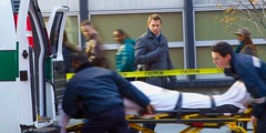 Un hombre mirando a dos paramédicos que meten a alguien en una ambulancia