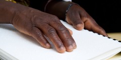 Persoană citind o publicație în Braille