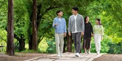 Fiatalok vidáman beszélgetnek a szüleikkel egy parkban sétálva