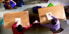 Un garçon triche à un examen en tendant un papier à un autre garçon