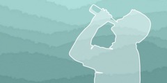 A silhouette of a man with his head tipped back as he drinks from a bottle