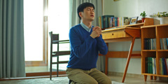 Mlad moški na kolenih goreče moli.