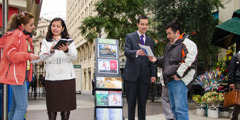 Dëshmitarët e Jehovait pranë një stende të lëvizshme me literaturë, u japin mesazhin e Biblës kalimtarëve