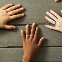 Three young people’s left hands, each with a ring on one finger