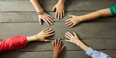 Six young people’s left hands, each with a ring on one finger