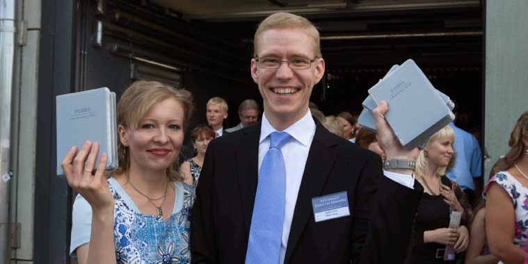 A smiling couple hold up copies of the newly released New World Translation in Estonian