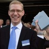 Một người đàn ông tươi cười cầm một cuốn Kinh Thánh Bản dịch Thế Giới Mới được ra mắt trong tiếng Estonia