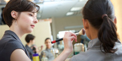 Una maquilladora aplica cosmètics a una model