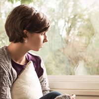 A depressed girl stares out a window