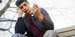 Ein verzweifelter junger Mann betrachtet eine Kette mit einem Herzanhänger in seiner Hand