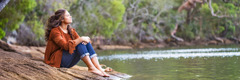 Une adolescente est assise au bord d’un lac
