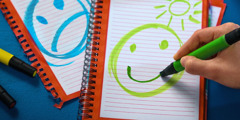 Um jovem faz um desenho de uma carinha feliz e outra triste