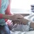 한 젊은 여자가 병실에 누워 있는 연로한 환자의 손을 잡고 있는 모습