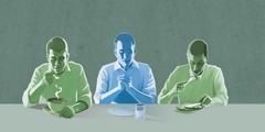 n home fent oració davant d’un plat buit mentre dos homes mengen al seu costat