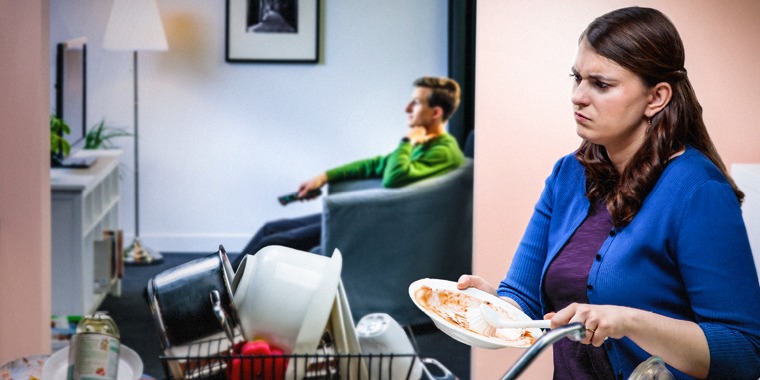 A wife is angry when her husband watches television while she washes the dishes