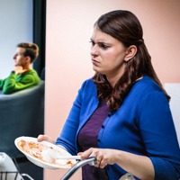 A wife is angry when her husband watches television while she washes the dishes