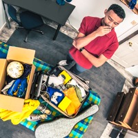 A young man packs his belongings and prepares to leave home