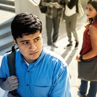A young man feels tempted to join two boys looking at an electronic device