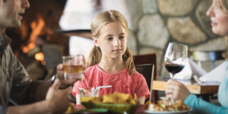 A little girl observes her parents drink alcohol
