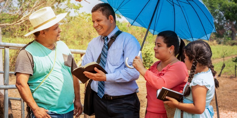 Óscar Serpas, accompanied by his wife and daughter, preaches to a man