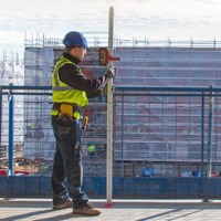 A member of the architectural team uses a tripod-mounted laser level