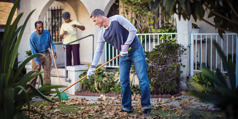 A man who is coping with suicidal thoughts smiles as he helps another man rake leaves