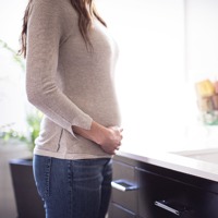 A pregnant woman stands in front of a mirror
