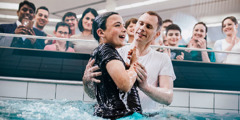 A boy getting baptized by complete water immersion.