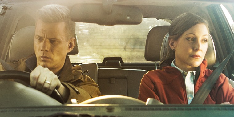 A husband and wife angrily stare out the windows of a car
