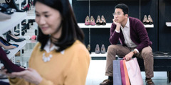 Ein Ehemann wartet ungeduldig, während seine Frau Schuhe kauft