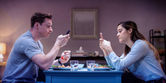 Ein Ehepaar isst gemeinsam und beide beschäftigen sich gleichzeitig mit ihrem Smartphone.