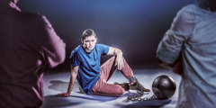 Ein Jugendlicher sitzt auf dem Boden und eine große Kugel ist an sein Fußgelenk gekettet