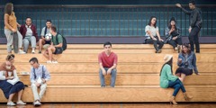 Ein Jugendlicher sitzt alleine, während seine Schulkameraden in Gruppen zusammensitzen