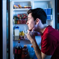A young man decides which foods to eat from a refrigerator