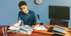 Ein Jugendlicher macht am frühen Abend seine Hausaufgaben und vermeidet Ablenkungen.