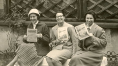 Irma and her two pioneer partners sitting on a bench holding the “Watchtower” and “Awake!” magazines.