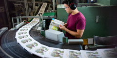 A brother checking the quality of the printed books as they come off an assembly line.