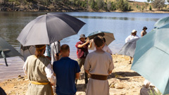 Crew members using umbrellas to shield the cast from the sun.